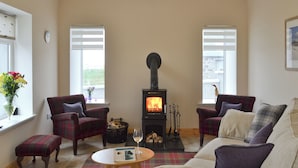 A cozy living room with a fireplace, plaid furniture, and a window with a view.