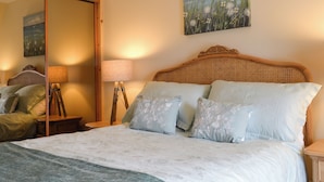 A bedroom with a bed, a nightstand, a lamp, and a mirror.