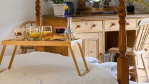A wooden bed with a white comforter, a wooden bedside table with breakfast items including croissants, juice glasses, and a vase with a single flower. - 4 bedroom accommodation in Arthog, near Dolgellau (Arthog, near Dolgellau)