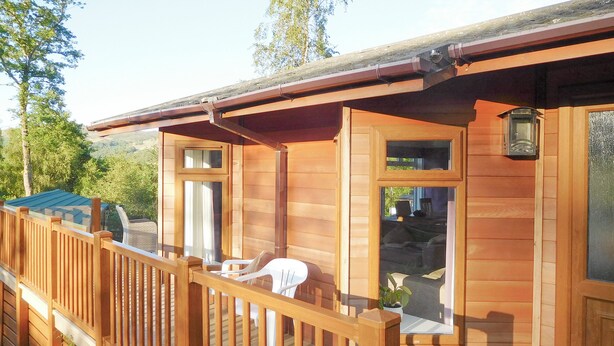 A wooden cabin with a deck, a door with a window, and a small porch area.