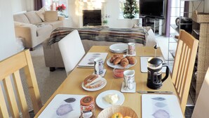 A dining area with a table set for breakfast, including croissants, jam, and coffee.