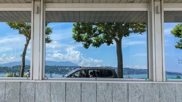 A modern building with large windows overlooking a body of water and a distant landscape.