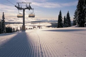 A ski lift chair suspended over a snow-covered slope with a forested area in the background. - ☀️🌲⛰Venez prendre un bol d'air pur au coeur de la Réserve Naturelle du Haut-Jura (Mijoux)