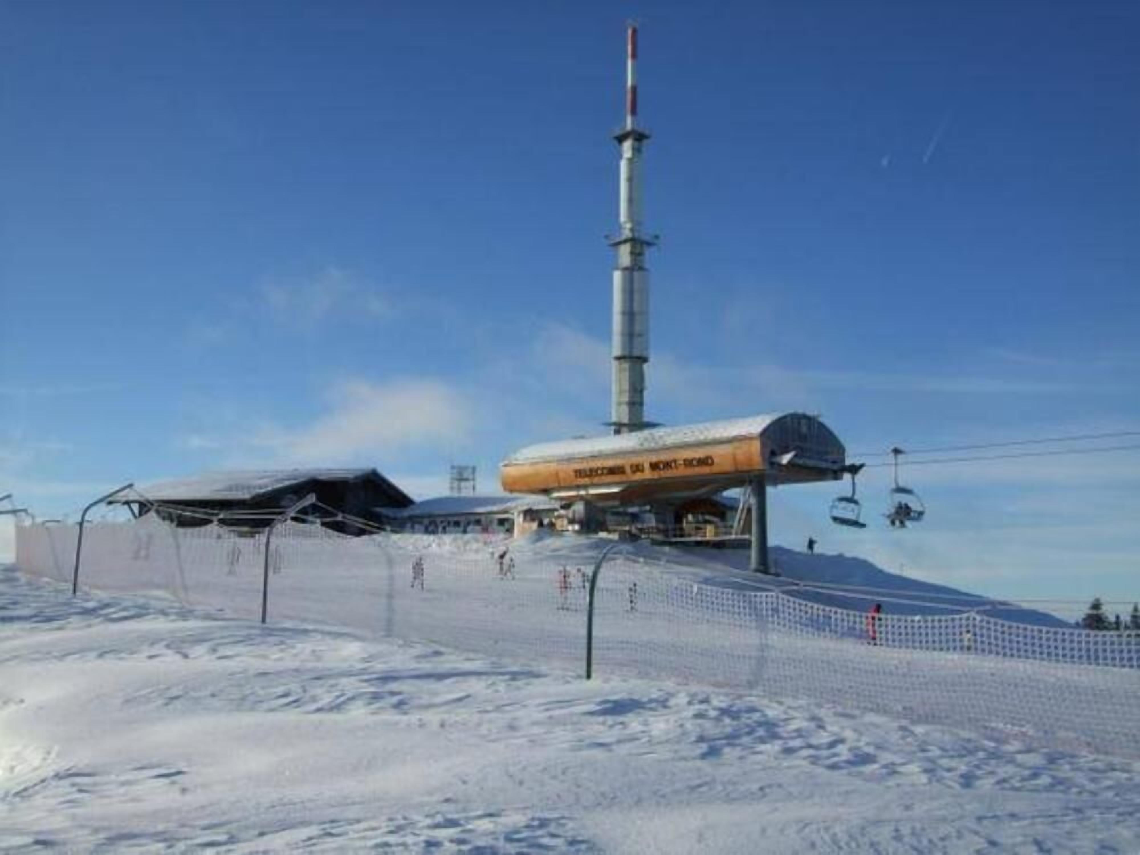 A ski lift with a cable car system, a tall communication tower, and a covered area with a sign.