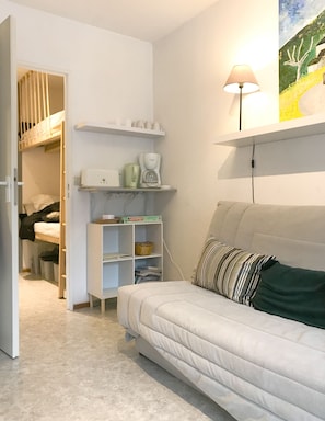 A cozy room with a bed, a sofa, a shelf with cups, a coffee maker, and a lamp. - ☀️🌲⛰Venez prendre un bol d'air pur au coeur de la Réserve Naturelle du Haut-Jura (Mijoux)