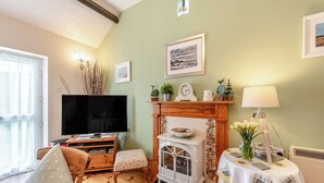 Ein gemütliches Wohnzimmer mit Fernseher, Kamin und Essbereich mit Tisch und Stühlen.
