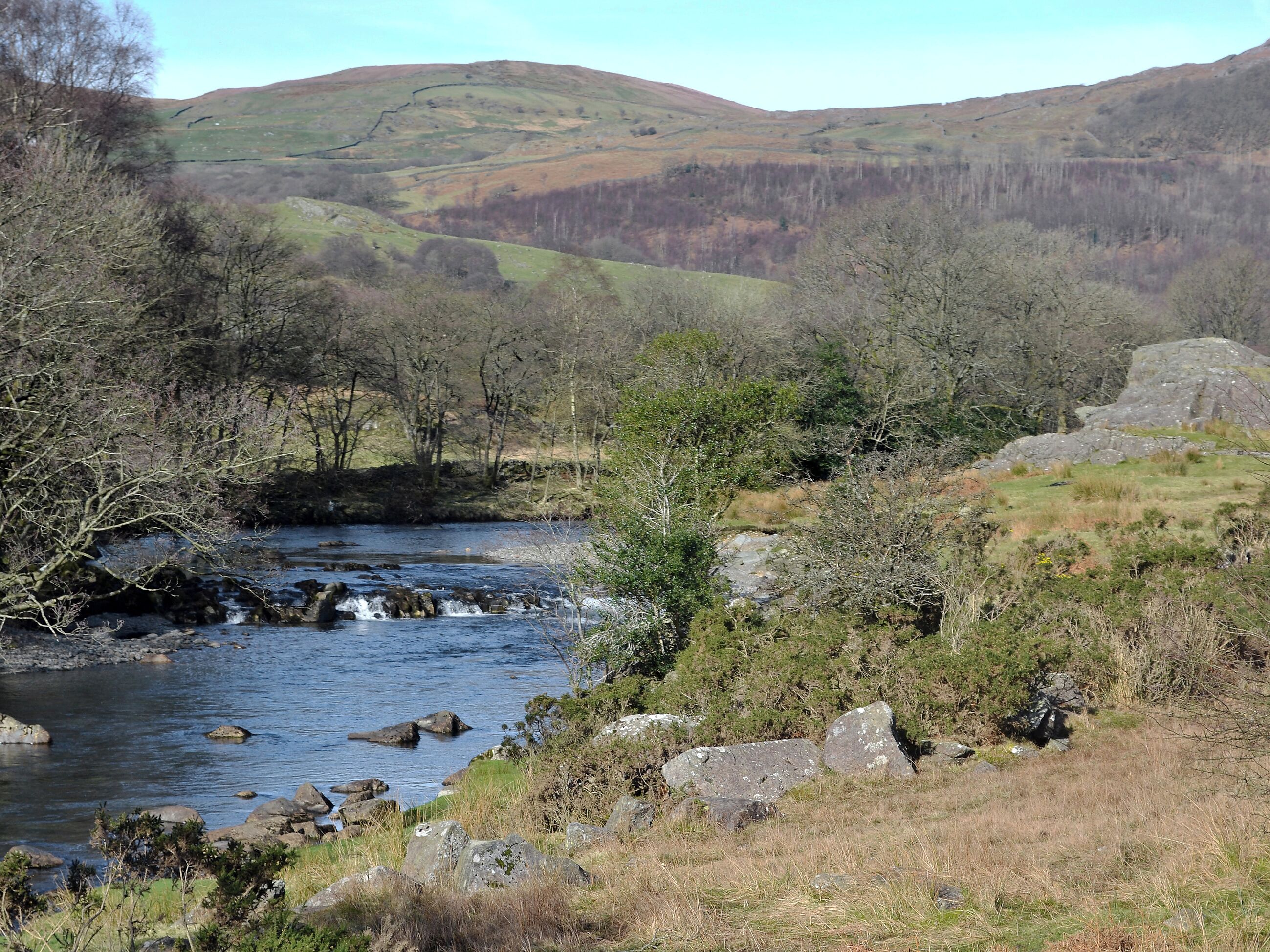 A river flowing through a valley with hills in the background.