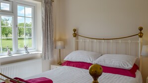 A neatly made bed with white and pink bedding, a wooden headboard, and a view of greenery through the window. - 2 bedroom accommodation in Upton, Didcot (Upton, Didcot)