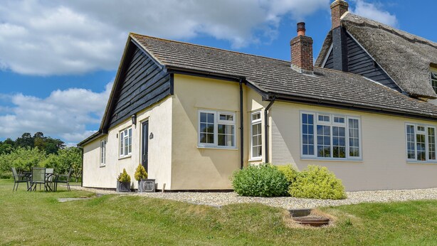 A two-story house with a thatched roof, a well-maintained lawn, and a small patio area. - 2 bedroom accommodation in Upton, Didcot (Upton, Didcot)