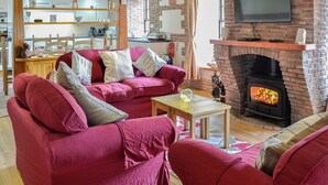 A cozy living room with a fireplace, red sofas, and a wooden ceiling. - Bridge House - UKC1340 (Heasley Mill, near South Molton)