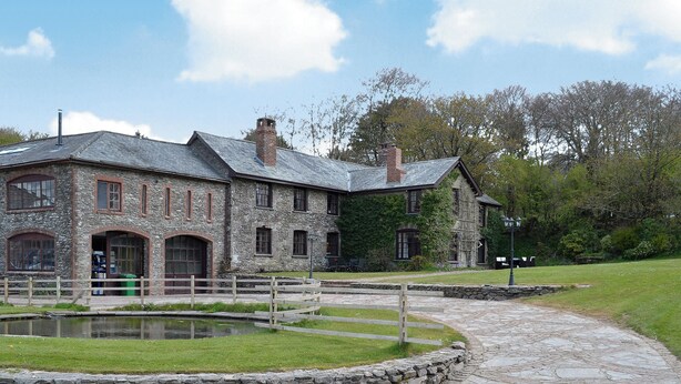 A stone building with a pond and a stone pathway. - Bridge House - UKC1340 (Heasley Mill, near South Molton)