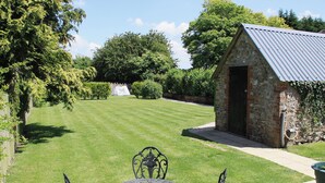 A well-maintained lawn with a stone building and a metal table with chairs. - 2 bedroom accommodation in Bridge, near Chard (Bridge, near Chard)