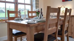 A dining table set with plates, glasses, and a vase of flowers. - 2 bedroom accommodation in Hungladder, near Uig (Hungladder, near Uig)