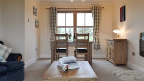 A cozy living room with a wooden table, two chairs, a sofa, and a window with curtains. - 2 bedroom accommodation in Hungladder, near Uig (Hungladder, near Uig)