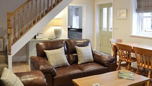 A living room with a brown leather sofa, a wooden coffee table, and a staircase.