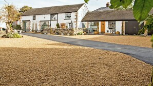 A two-story building with a gravel driveway and a stone wall. - Lavender Cottage - UK4061 (Buxton)