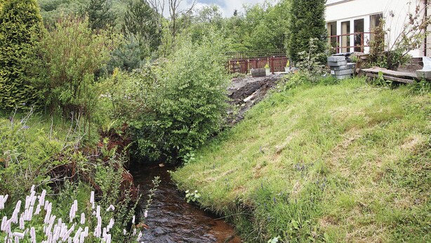 A house with a sloped roof, a small garden, and a stream running through the property. - Stob-Ban View - S4582 (Achintee, Fort William)