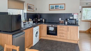 A compact kitchen with a washing machine, a built-in oven, and a small refrigerator. - Stob-Ban View - S4582 (Achintee, Fort William)