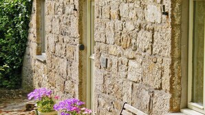 A stone building with a bench outside, a door, and a window. - 2 bedroom accommodation in Godolphin Cross, Helston (Godolphin Cross, Helston)