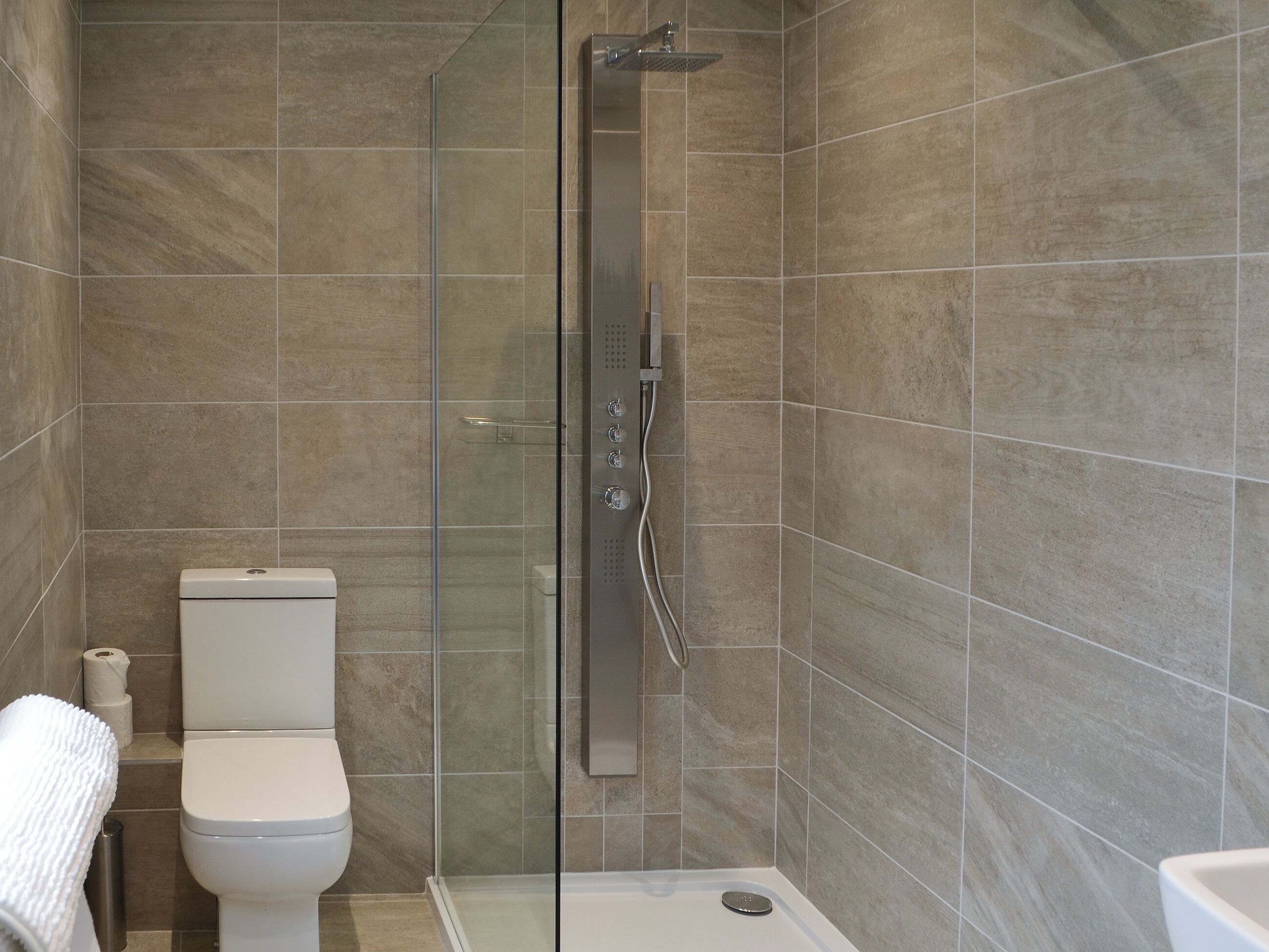 Une salle de bain moderne dotée d’une douche à parois de verre, de toilettes et d’une baignoire.