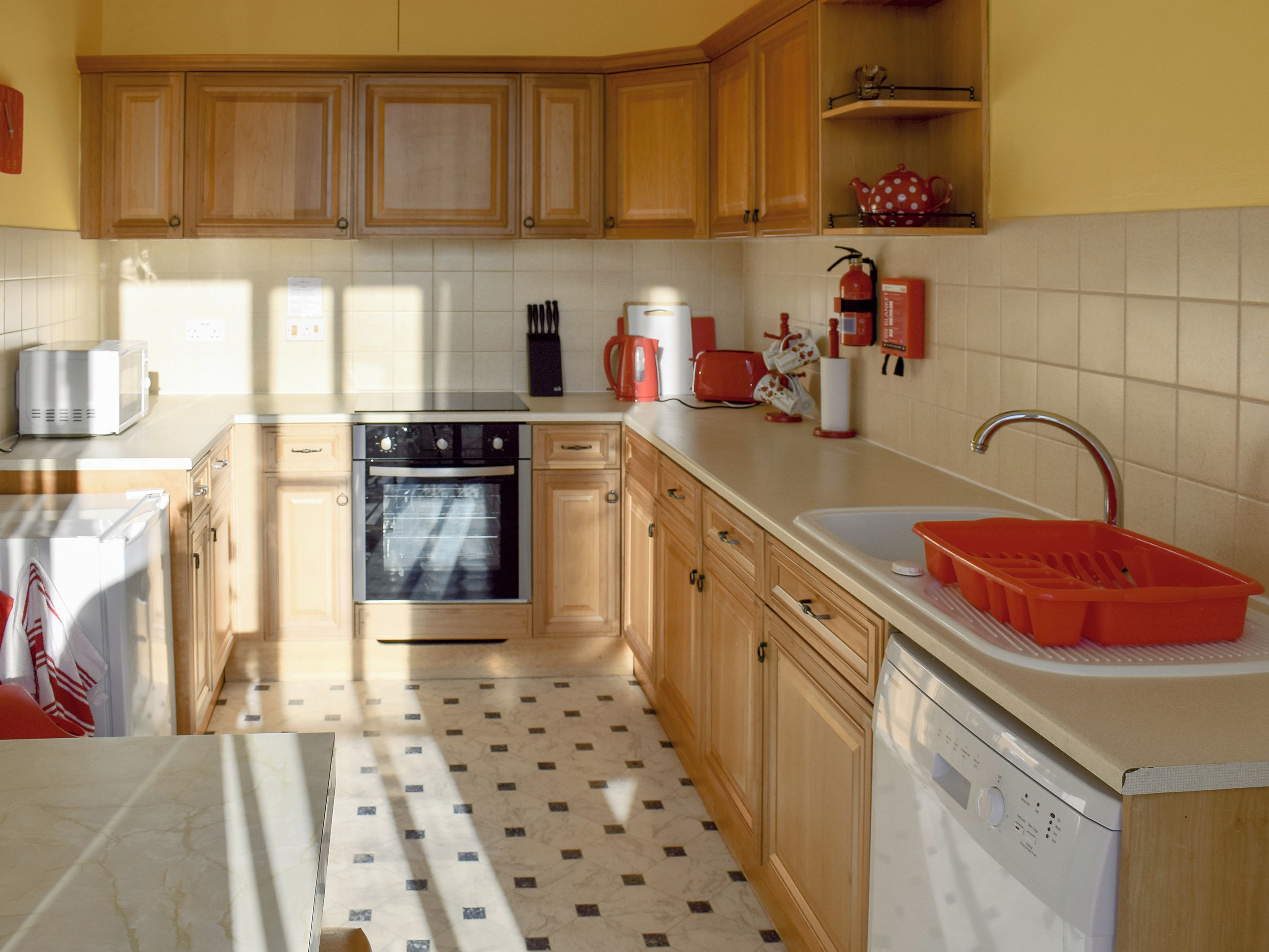 A kitchen with wooden cabinets, a dishwasher, an oven, and a sink.