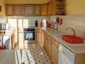 Una cocina con armarios de madera, lavavajillas, horno y fregadero.