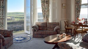A cozy living room with a sofa, a round coffee table, and a dining table set for two. A large window offers a scenic view of rolling hills. - 2 bedroom accommodation in Saltburn-by-the-Sea (Saltburn-by-the-Sea)