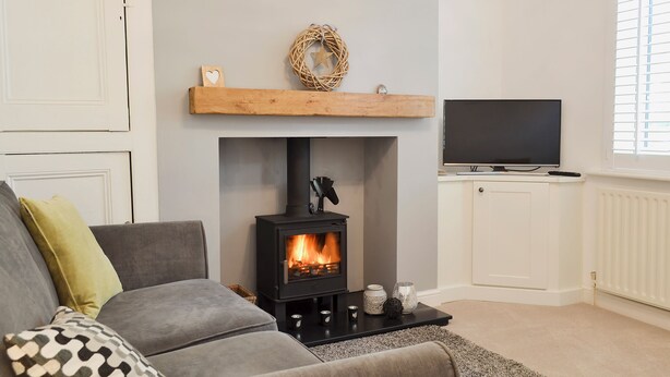Una sala de estar con chimenea, un sofá, un televisor y un ventanal con persianas.