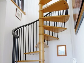 A spiral staircase with wooden steps and black railings.