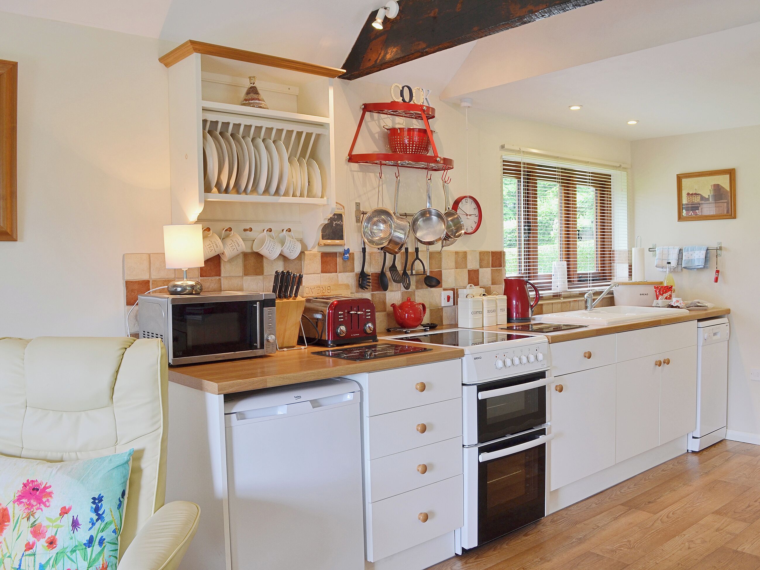 A kitchen with white cabinets, a microwave, a toaster, a kettle, and a sink.