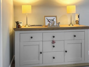 Een witte kast met twee lampen, een lijst met foto en een kleine beeldjes.