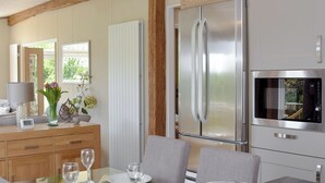 A modern kitchen with a stainless steel refrigerator, an oven, and a dining area with a table set for two.