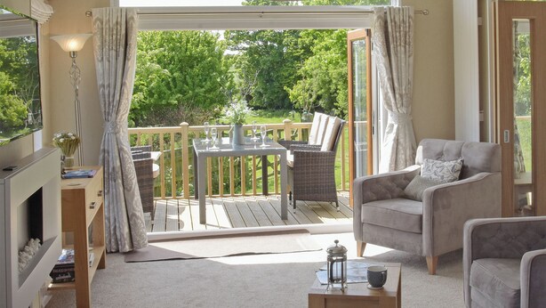 A room with a balcony, a sofa, a table, and a lamp.