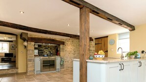 A kitchen with stone walls, a large island, and a wooden ceiling beam. - The Farmhouse at Higher Westwater (Axminster)