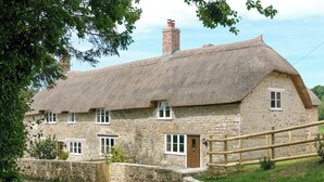 A stone house with a thatched roof, a wooden gate, and a stone wall. - The Farmhouse at Higher Westwater (Axminster)