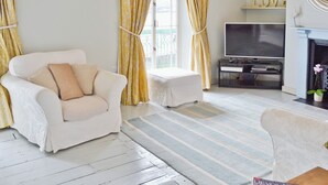 A living room with a white sofa, a television, and a fireplace. - 3 bedroom accommodation in Instow, Bideford (Instow, Bideford)