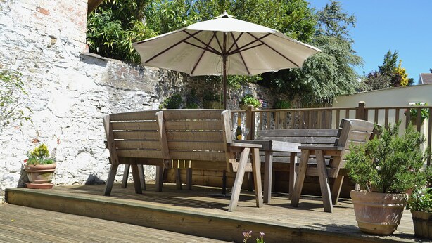 An outdoor wooden deck with a table and chairs under a large umbrella. - 3 bedroom accommodation in Instow, Bideford (Instow, Bideford)