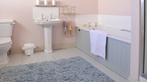 A bathroom with a toilet, sink, and bathtub. There is a blue rug on the floor. - 3 bedroom accommodation in Instow, Bideford (Instow, Bideford)