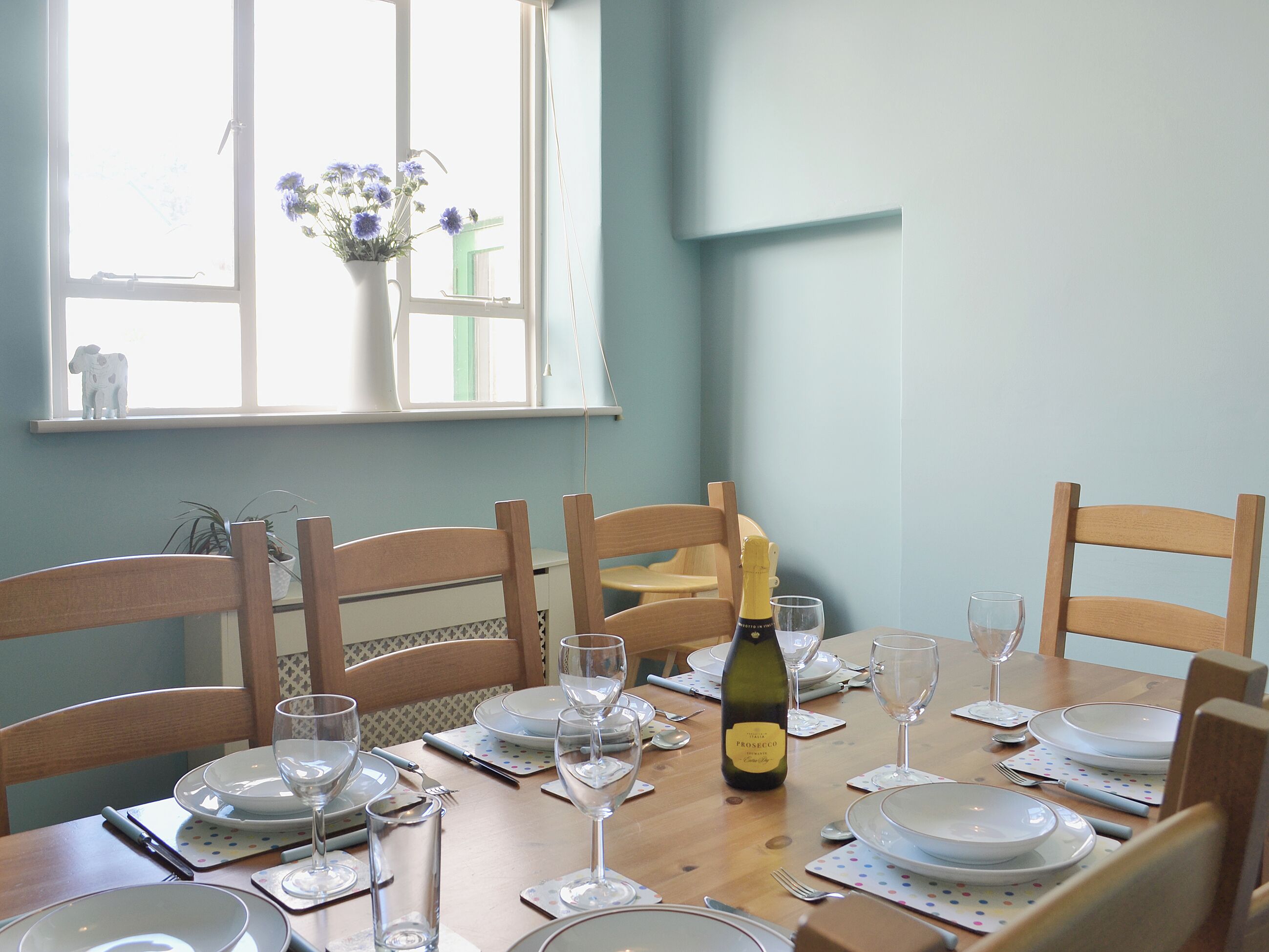 Une table à manger dressée pour six personnes, avec des assiettes, des verres et une bouteille de vin.