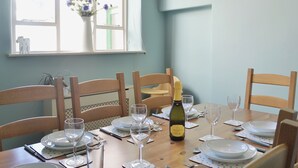A dining table set for six with plates, glasses, and a bottle of wine. - 3 bedroom accommodation in Instow, Bideford (Instow, Bideford)