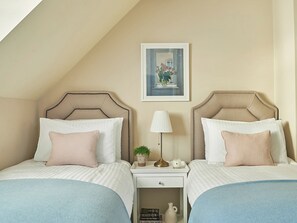 A bedroom with two beds, a nightstand with a lamp, a small plant, and a framed picture on the wall. - 4 bedroom accommodation in Pickering (Pickering)