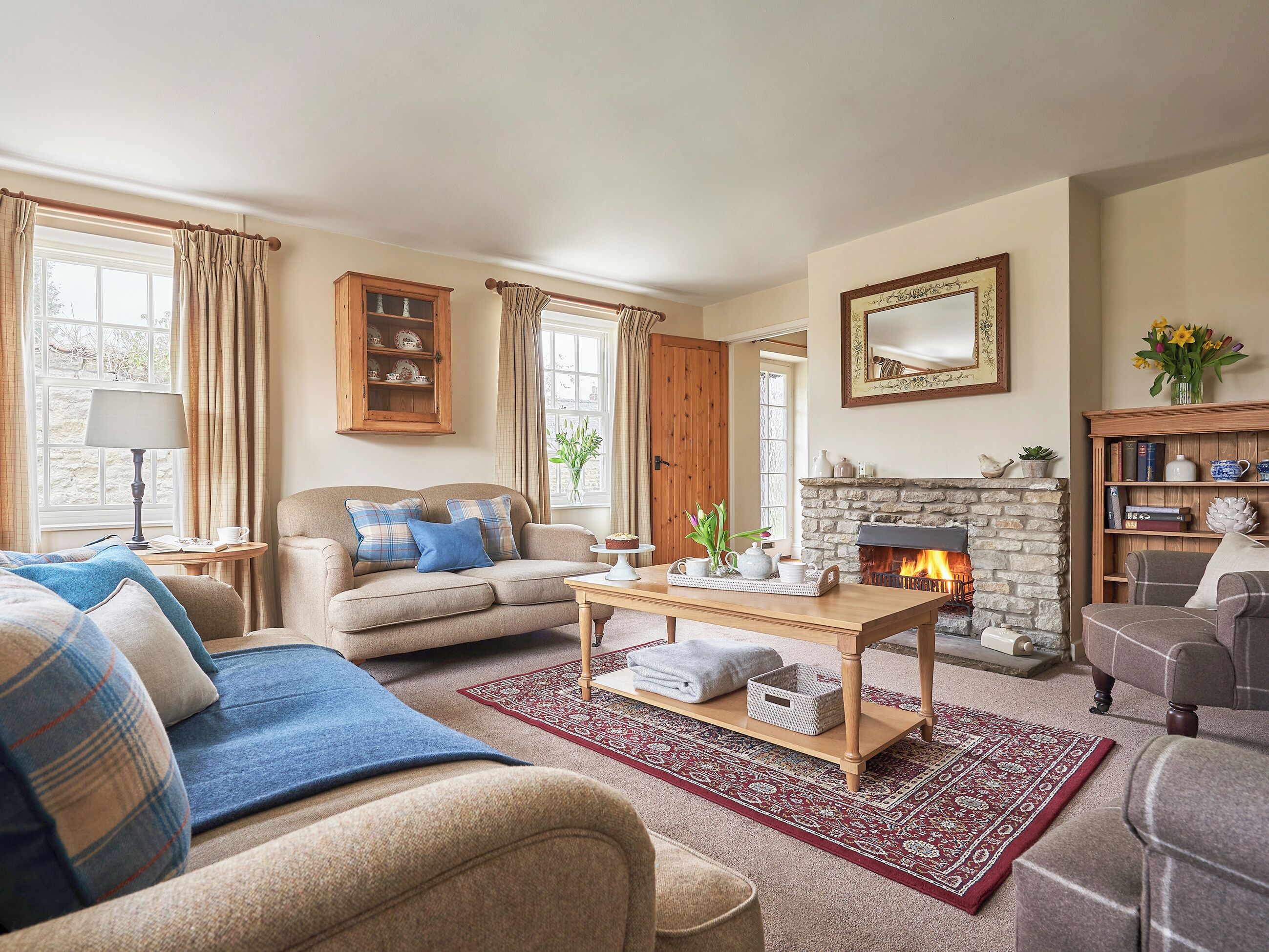A cozy living room with a fireplace, a sofa set, a coffee table, and a bookshelf.