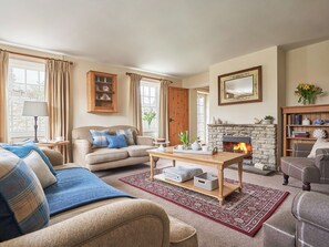 A cozy living room with a fireplace, a sofa set, a coffee table, and a bookshelf. - 4 bedroom accommodation in Pickering (Pickering)
