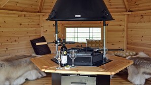 A wooden cabin interior with a black wood stove, wooden furniture, and fur rugs. - 2 bedroom accommodation in Glynarthen, near Cardigan (Glynarthen, near Cardigan)