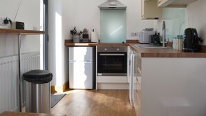Een moderne keuken met een koelkast, oven, magnetron en koffiezetapparaat.
