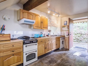 Une cuisine avec des meubles de rangement en bois, une cuisinière, un grille-pain et un lave-linge.