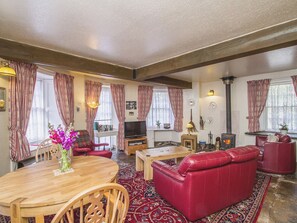 A living room with a wooden table, red leather sofa, and a fireplace.