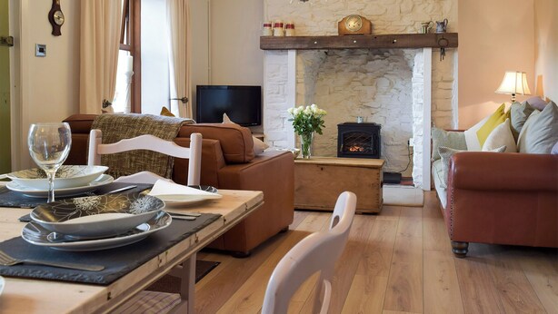 Ein gemütliches Wohnzimmer mit Kamin aus Stein, einem Fernseher und bequemen Sitzgelegenheiten.