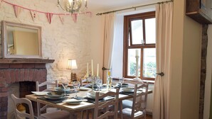 Ein Esszimmer mit Kamin aus Backstein, einer Kristallleuchter und einem Tisch, gedeckt für sechs Personen.