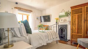 Ein Schlafzimmer mit Bett, Nachttisch, Lampe, Fernseher, Kamin und Kleiderschrank.